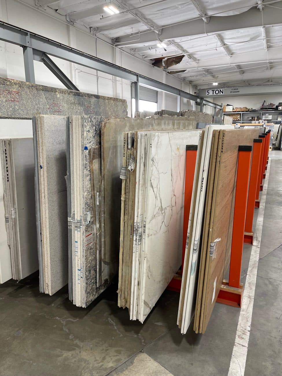Stone and quartz slabs racked upright in a warehouse, edges labelled