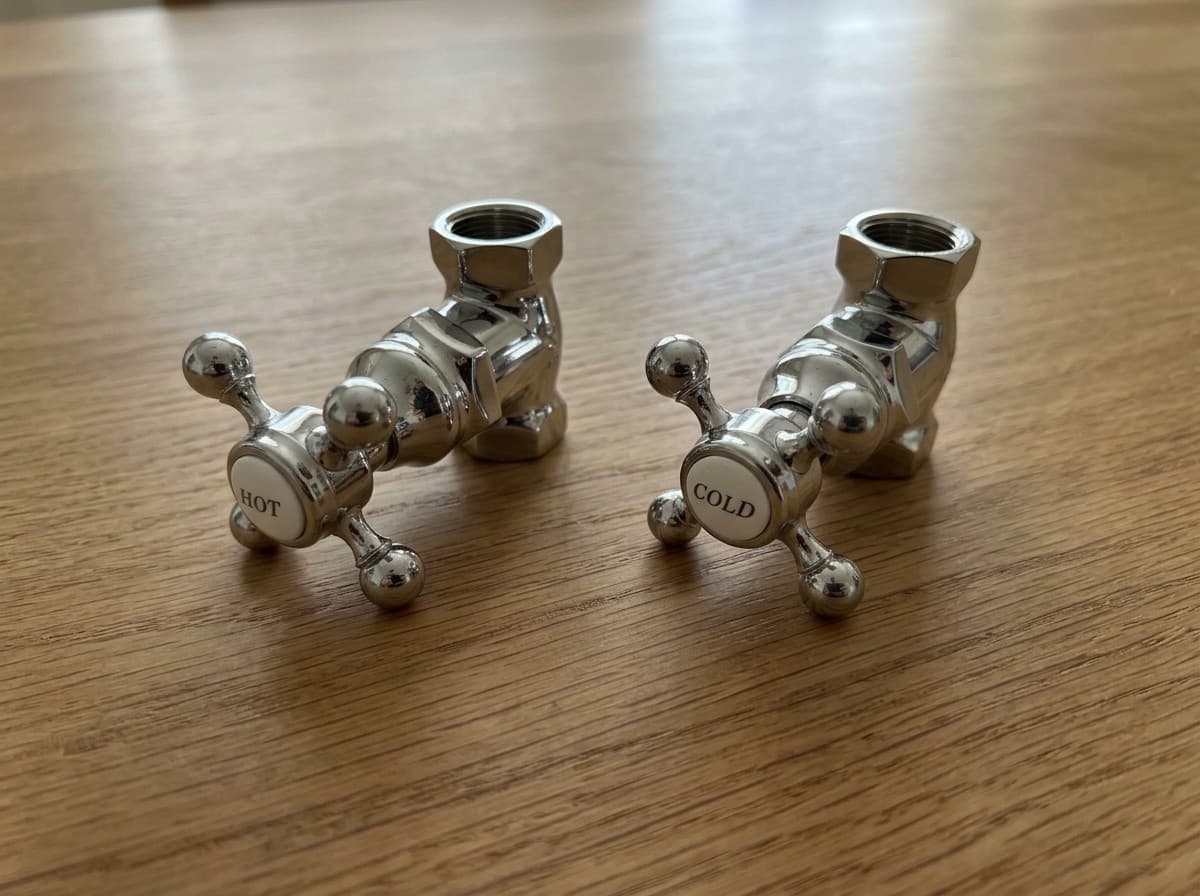 Newport Brass Fairfield shut off valves in polished nickel, pair, on a wood surface (AI-generated image)