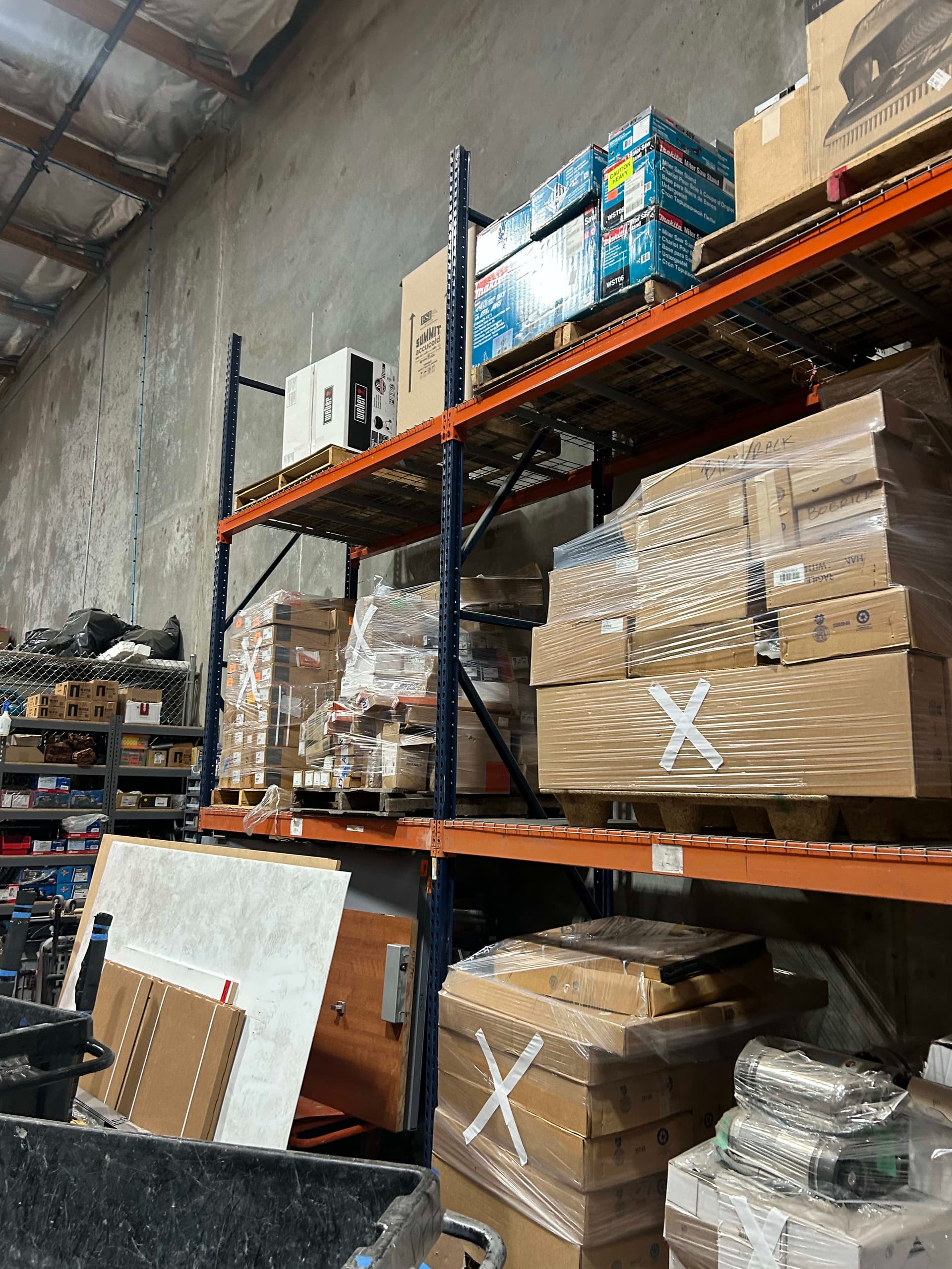 Surplus crate of new door hardware including handles, push bars, and hinges from healthcare projects
